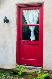Red door with a curtain in the window on a house.