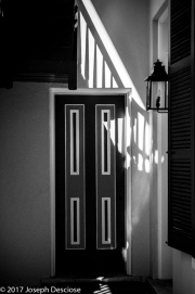 An architectural study of a wooden door in a hallway in black & white.