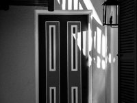 An architectural study of a wooden door in a hallway in black & white.