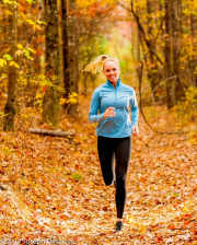 Woman dressed in fitness clothing running in a forest in autumn.