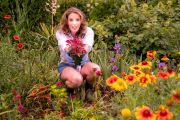 Sally McKay, television personality and baker in a garden setting surrounded by annual and perennial plants.