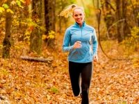 Woman dressed in fitness clothing running in a forest in autumn.