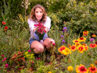 Sally McKay, television personality and baker in a garden setting surrounded by annual and perennial plants.